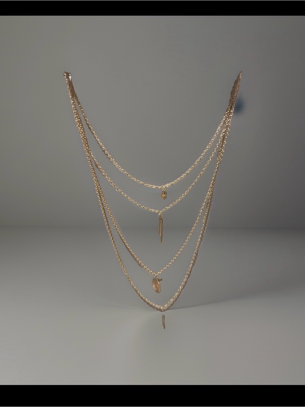 multi-strand layered gold chain necklace delicate dangling bar and coin charms.